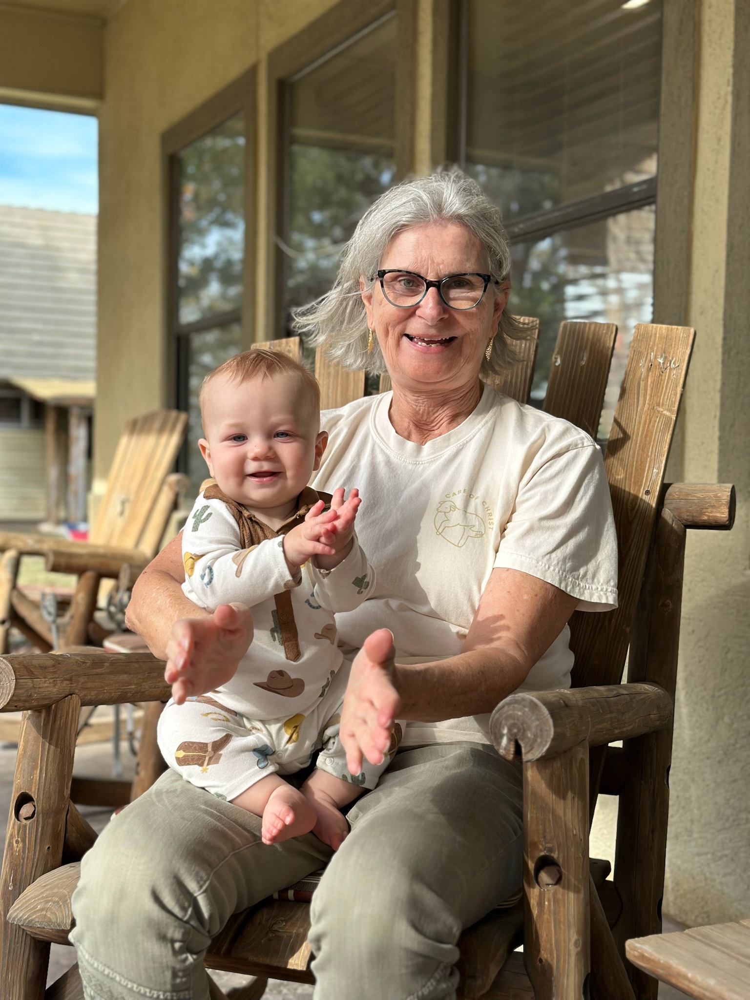 Grandma in a rocking chair with her grandchild, laughing on the porch